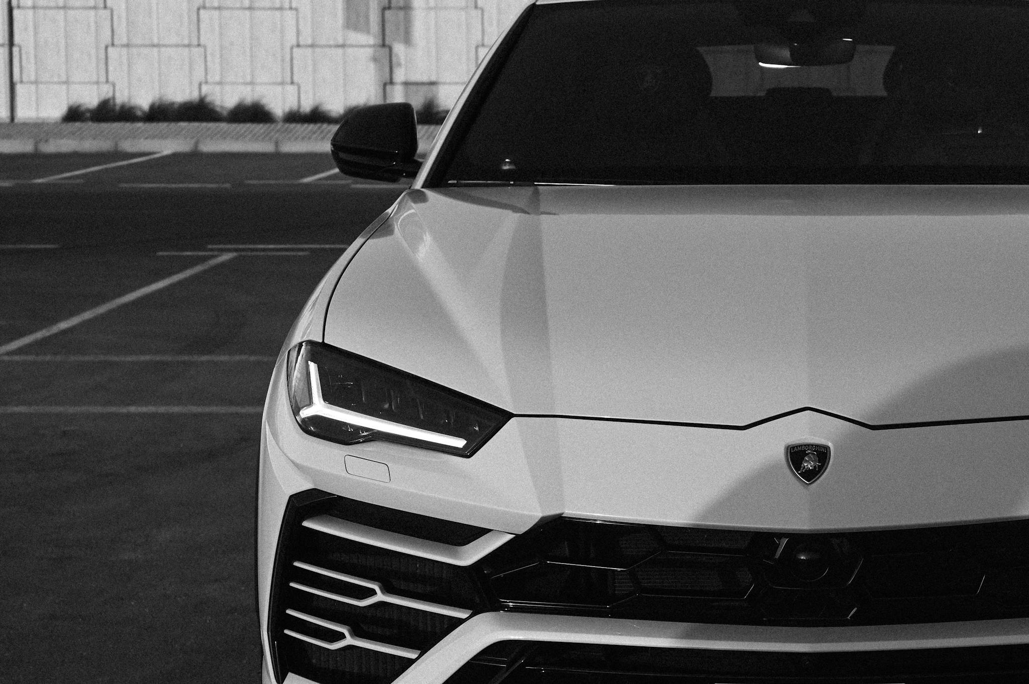 Artistic black and white photo of a luxury convertible car in a city parking lot.