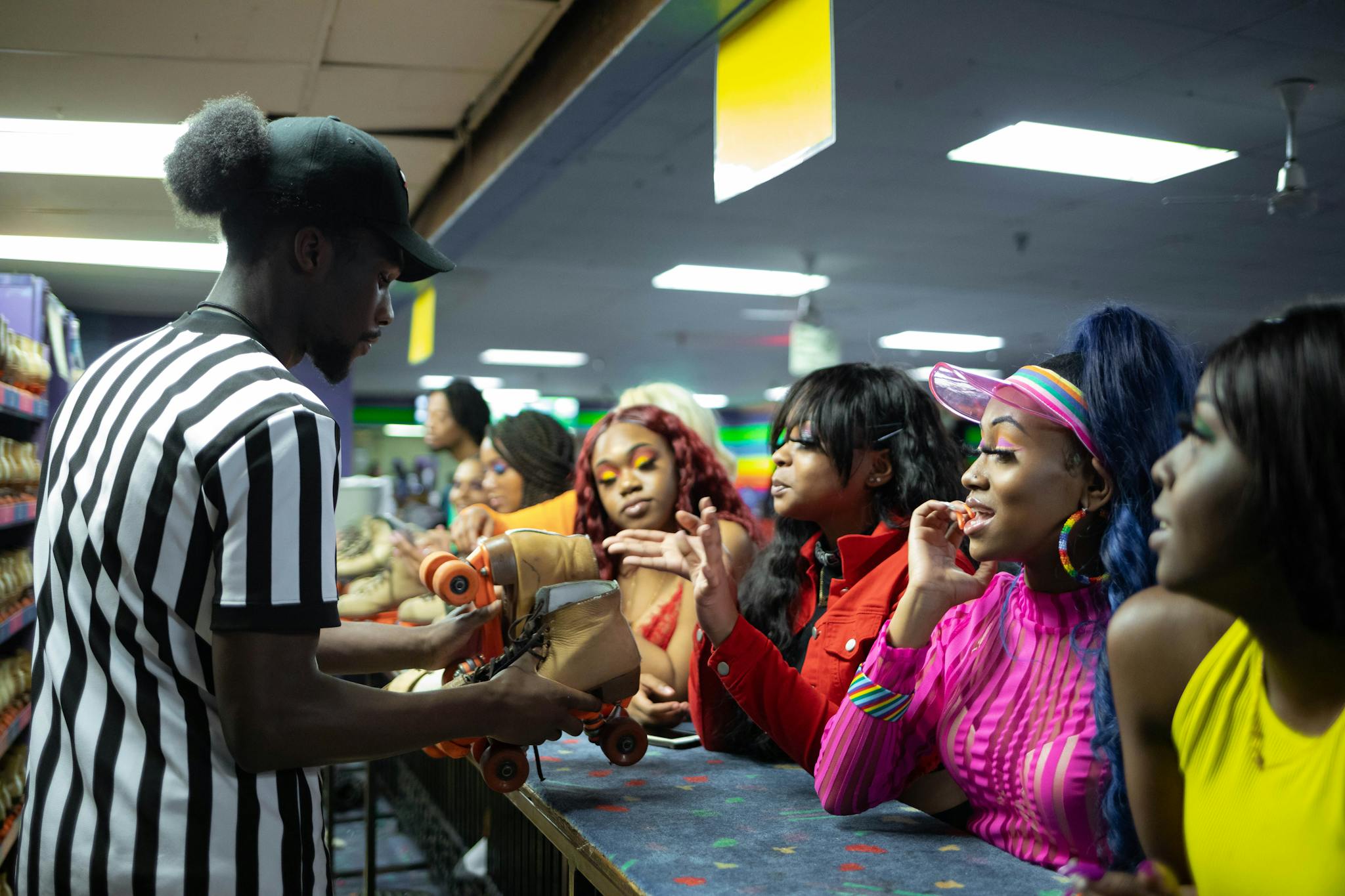 Group gathering around skate rental desk at a lively indoor roller rink.